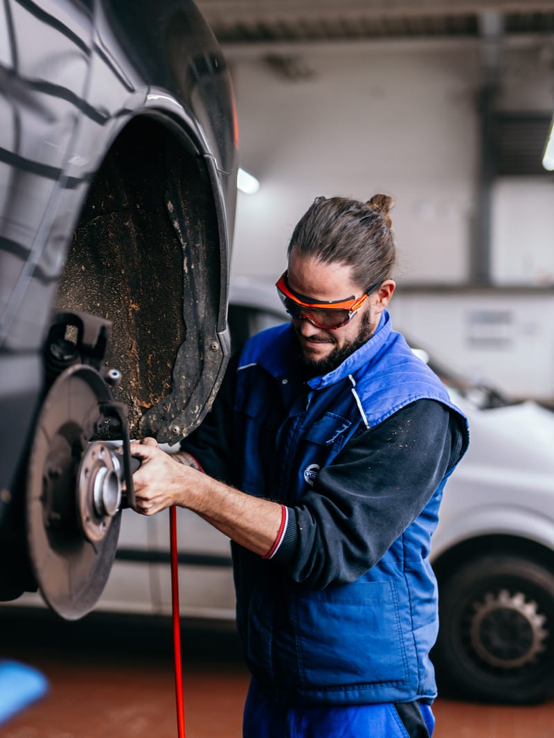 Arbeit an der Bremse mit Schutzbrille und Druckluftschrauber