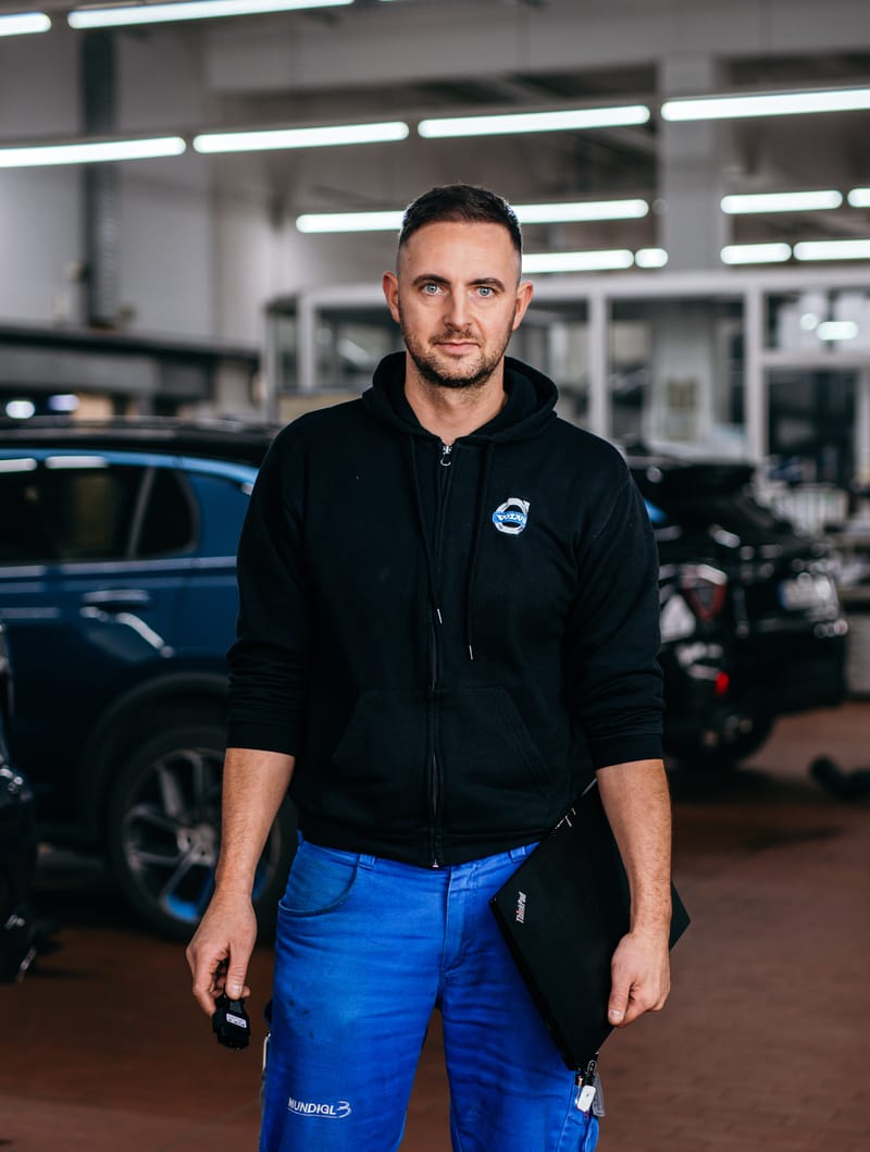 Ein Kollege im Volvo-Pullover steht in der hellen Werkstatthalle