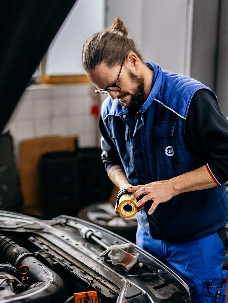 Ein Mechaniker prüft ein Bauteil im Motorraum